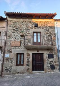 an old stone building with a balcony and a door at Casa Rural La Moraquintana in Santibáñez el Bajo