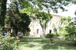 una grande casa bianca con alberi nel cortile di Le mas Rocamour a Roquemaure