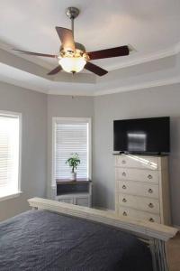 a living room with a ceiling fan and a dresser at Century Tree Lodge - Family & Football Friendly in College Station
