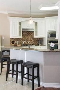 a kitchen with two stools and a counter with a sink at Century Tree Lodge - Family & Football Friendly in College Station