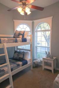 a bedroom with three bunk beds and a ceiling fan at Century Tree Lodge - Family & Football Friendly in College Station