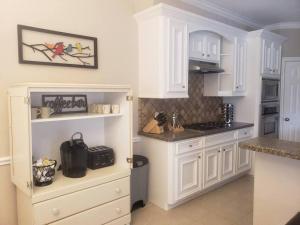 a white kitchen with white cabinets and a counter at Century Tree Lodge - Family & Football Friendly in College Station