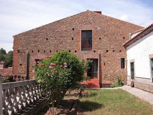 een stenen huis met een hek ervoor bij Casa Rural Finca Valvellidos in Jaraiz de la Vera