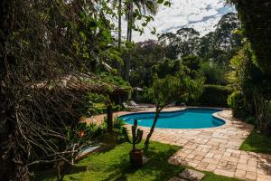 a swimming pool in a yard with trees at Pousada Recanto das Rosas in Bragança Paulista