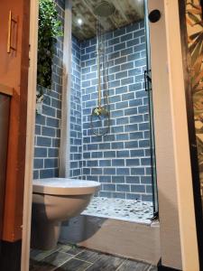 a bathroom with a toilet and a blue brick wall at La cachette sous les toits balnéo climatisé in Nantes