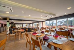 uma sala de jantar com mesas e cadeiras de madeira e um restaurante em Hotel Laghetto Stilo Borges em Gramado