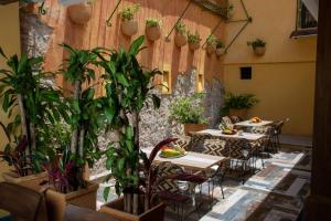 un patio avec des tables, des chaises et des plantes en pot dans l'établissement Casa Lorenza Hotel, à Carthagène des Indes
