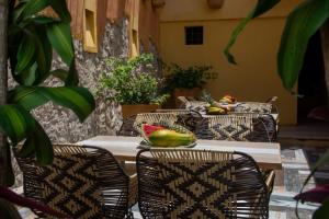 - une table avec des chaises et une assiette de fruits dans l'établissement Casa Lorenza Hotel, à Carthagène des Indes