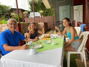 Bella Vista Ranch Ecolodge في توريالبا: ثلاثة أشخاص يجلسون على طاولة لتناول الطعام