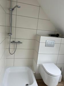a white bathroom with a shower and a toilet at Connect 9.1 in Dorum-Neufeld