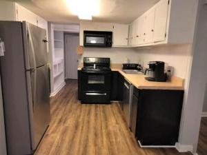 a kitchen with black and white appliances and wooden floors at 3 Bed 3 Bath House, Conveniently close to everything, Smart Tvs in all rooms whole house to yourself in New Bern