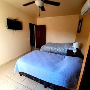 a bedroom with a blue bed and a ceiling fan at Como el Calor de tu hogar in San Pedro Sula