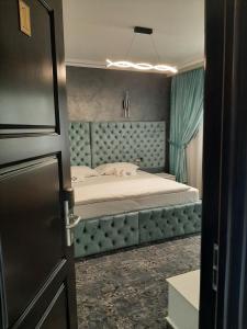 a bedroom with a bed with a blue head board at Pensiunea Ramina in Adjud