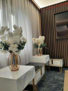 two vases with white flowers sitting on tables in a room at Pensiunea Ramina in Adjud