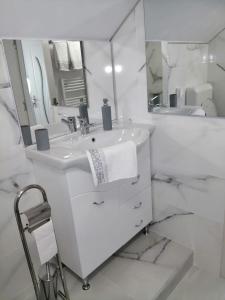 a white bathroom with a sink and a mirror at Lovely loft in Cluj-Napoca