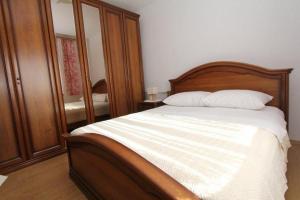 Schlafzimmer mit einem Bett mit einem Kopfteil aus Holz und einem Spiegel in der Unterkunft Apartments with a parking space Sveti Filip i Jakov, Biograd - 19436 in Sveti Filip i Jakov