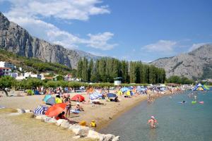 a crowd of people on a beach with umbrellas at Apartments with a parking space Omis - 5988 in Omiš