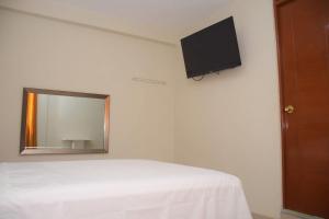 1 dormitorio con cama y espejo en la pared en Hostal El Gran Marquez G&J en Urbanizacion Buenos Aires