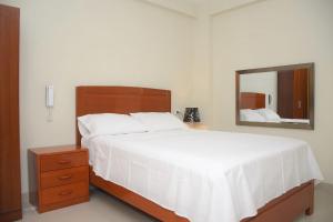 a bedroom with a large white bed and a mirror at Hostal El Gran Marquez G&J in Urbanizacion Buenos Aires