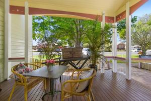 um alpendre com uma mesa e cadeiras em The Old Bank Gladstone Licensed Restaurant & Boutique Accommodation em Hat Head