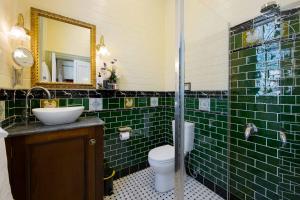 uma casa de banho com azulejos verdes, um WC e um lavatório. em The Old Bank Gladstone Licensed Restaurant & Boutique Accommodation em Hat Head