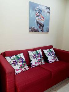 a red couch with three pillows on it at Hermoso Apartamento in San Pedro Sula