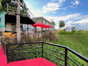 a balcony with red tables and umbrellas in front of a building at Pua Panorama Resort in Nan +17 photos