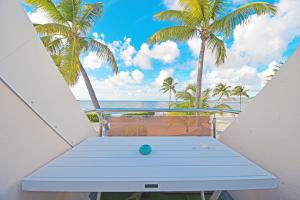 a blue table on a balcony with palm trees at Deja Blue - Comfortable Beachfront condo in Marigot