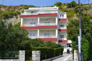 Apartments by the sea Duce, Omis - 8378 في دوغي رات: عمارة سكنية حمراء وبيضاء على تلة