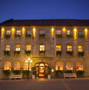 een groot stenen gebouw met verlichting aan bij Hotel Goldener Anker in Bayreuth
