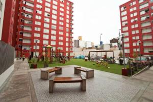 einen Park mit Spielplatz mit Bänken und Rutsche in der Unterkunft Departamento céntrico y moderno, exelente ubic. in Lima