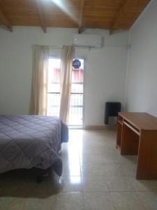 a bedroom with a bed and a desk and a window at Casa tipo duplex con patio y parrilla. Muy cómoda in Neuquén