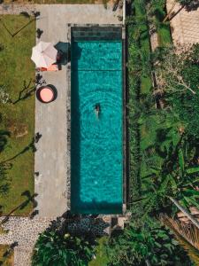 een uitzicht over een zwembad met een persoon in het water bij Suara Air Luxury Villa Ubud in Ubud