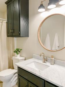 a bathroom with a sink and a toilet and a mirror at The Ruby - Modern Updated 4/2 Home Near ACU in Abilene