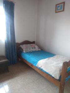 a small bed in a room with a blue curtain at Casa tipo duplex con patio y parrilla. Muy cómoda in Neuquén