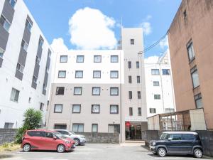 two cars parked in a parking lot in front of a building at Tabist Rays Hotel Suisen in Miyazaki
