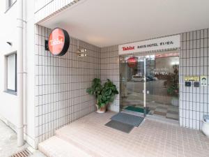 une porte d'entrée d'un bâtiment avec une usine de pot dans l'établissement Tabist Rays Hotel Suisen, à Miyazaki