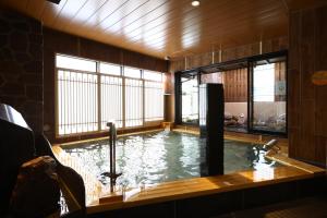 a swimming pool in a room with a tub at Onyado Nono Sendai Natural Hot Spring in Sendai