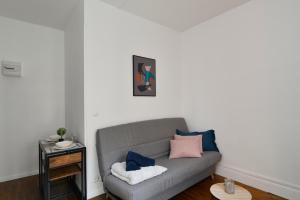 sala de estar con sofá gris con almohadas azules y rosas en Home Group, en Saint-Quentin
