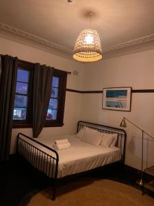 a bedroom with a bed and a chandelier at Charing Cross Hotel in Sydney