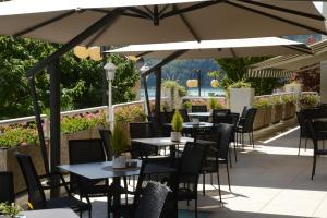 an outdoor patio with tables and chairs and umbrellas at Hotel Ambassador in Levico Terme