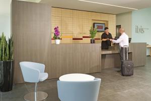 two people standing at a reception desk in a lobby at ibis Heverlee Leuven in Leuven