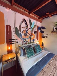 a bedroom with a bed with a painting on the wall at 13 Cielos Hostel in San Cristóbal de Las Casas