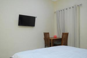 a bedroom with a bed and a table and a flat screen tv at Griya Agnes Semarang Mitra RedDoorz in Kalibanteng-kidul