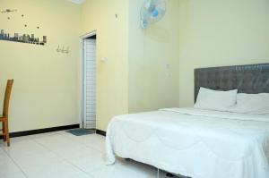 a bedroom with a white bed and a fan at Griya Agnes Semarang Mitra RedDoorz in Kalibanteng-kidul