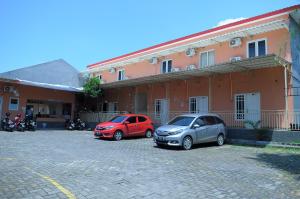 two cars parked in a parking lot in front of a building at Griya Agnes Semarang Mitra RedDoorz in Kalibanteng-kidul