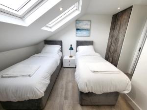 2 camas individuales en una habitación con tragaluces en Garland Modern 4 Bedroom Central Apartment London, en Finchley