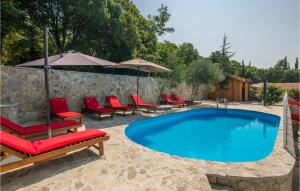 a swimming pool with red chairs and a stone wall at 4 Bedroom Stunning Home In Omisalj in Omišalj