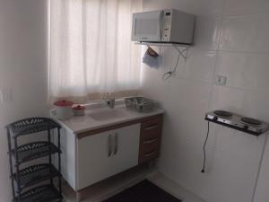 a small kitchen with a sink and a microwave at LOFT3 COMPLETO AR CANAIS ASSINAT GARAGEM INTERNET Prox Aparecida e Industrias in Pindamonhangaba