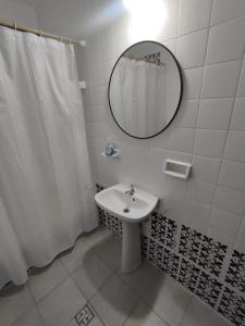 ein weißes Badezimmer mit einem Waschbecken und einem Spiegel in der Unterkunft Casa Barrio Sur COMODA in San Miguel de Tucumán